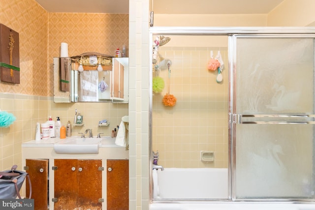 bathroom featuring tile walls, shower / bath combination with glass door, and vanity