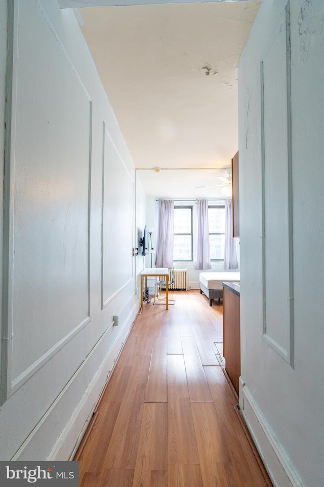 hallway with light wood-type flooring and radiator heating unit