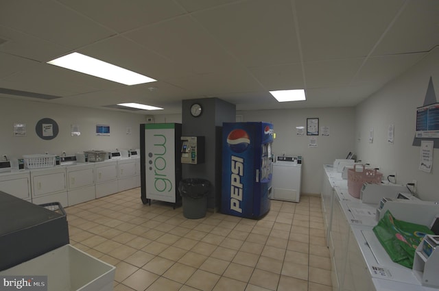 interior space featuring washing machine and clothes dryer, white cabinetry, a drop ceiling, and light tile flooring