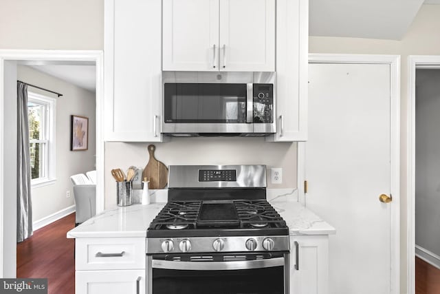 kitchen featuring appliances with stainless steel finishes, dark hardwood / wood-style floors, light stone countertops, and white cabinetry