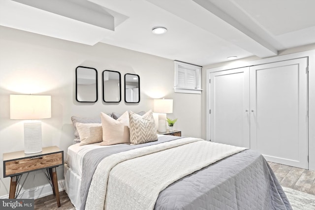 bedroom featuring a closet, light wood-type flooring, and beamed ceiling