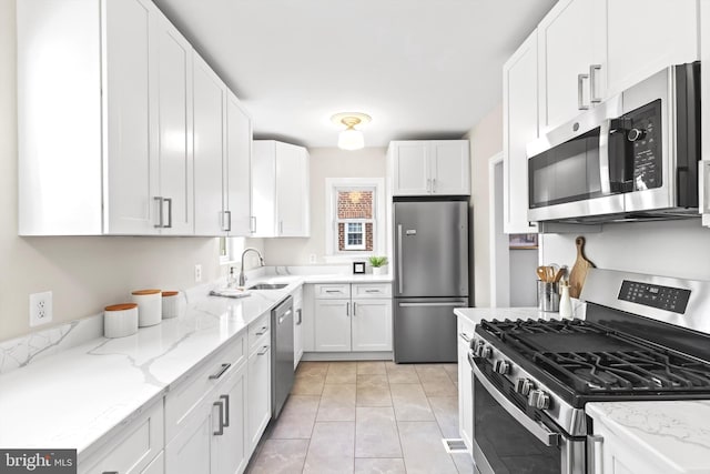 kitchen featuring white cabinets, sink, light tile floors, and stainless steel appliances