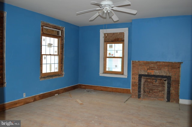 unfurnished living room featuring a brick fireplace and ceiling fan