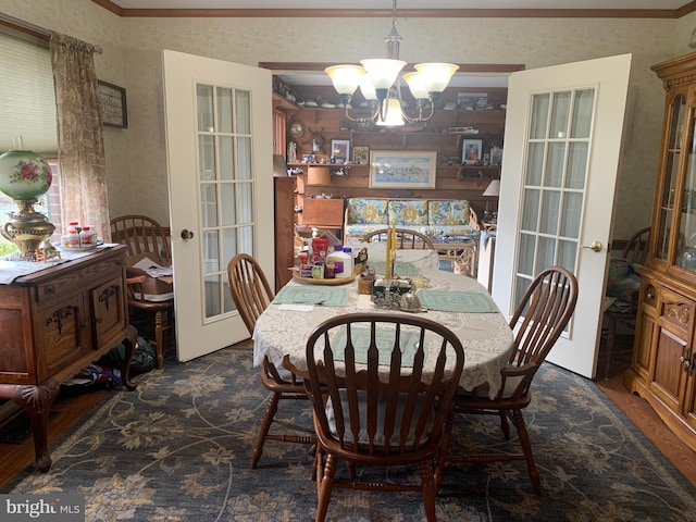 dining space with a notable chandelier, ornamental molding, dark wood-type flooring, and french doors