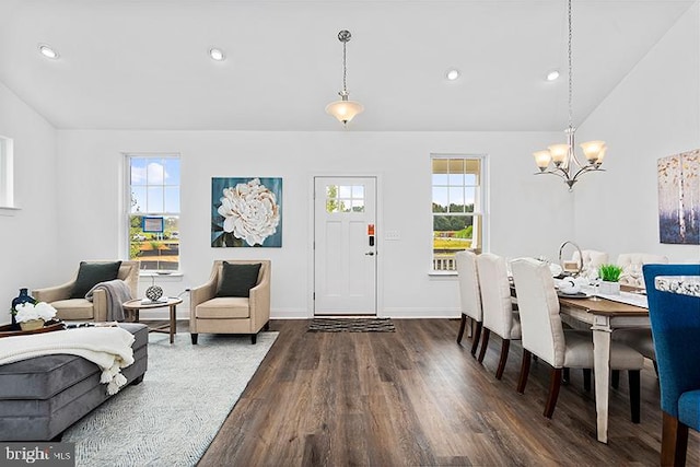 dining space featuring dark hardwood / wood-style flooring, lofted ceiling, and a chandelier