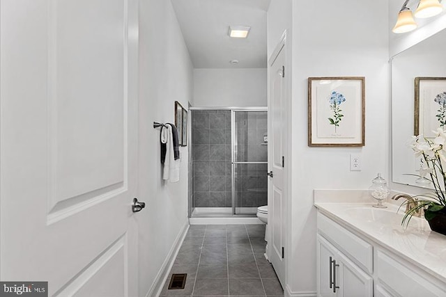 bathroom featuring toilet, a shower with door, large vanity, and tile floors