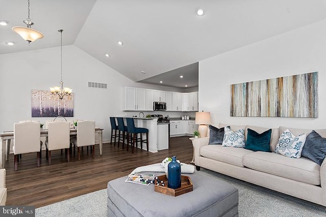 living room featuring a notable chandelier, dark wood-type flooring, and high vaulted ceiling