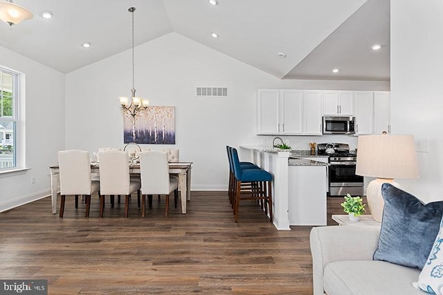 kitchen featuring dark wood-type flooring, stainless steel appliances, decorative light fixtures, a chandelier, and white cabinets