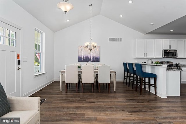 dining room with a notable chandelier, a wealth of natural light, high vaulted ceiling, and dark hardwood / wood-style floors