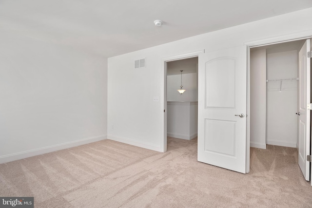 unfurnished bedroom featuring light colored carpet, a spacious closet, and a closet