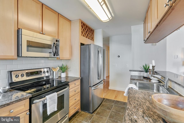 kitchen with light brown cabinetry, sink, dark tile flooring, appliances with stainless steel finishes, and backsplash