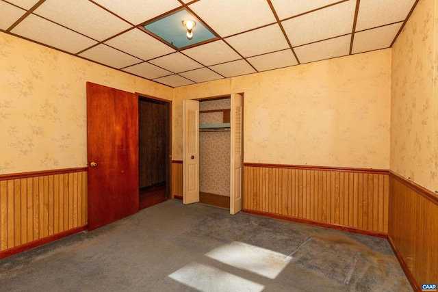 spare room featuring dark carpet and a paneled ceiling