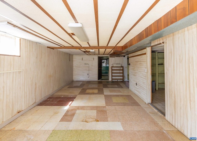 basement featuring wood walls and light tile floors