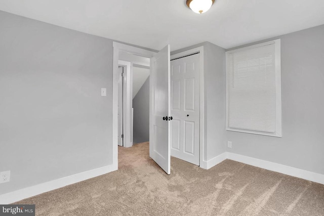 unfurnished bedroom with a closet and light colored carpet