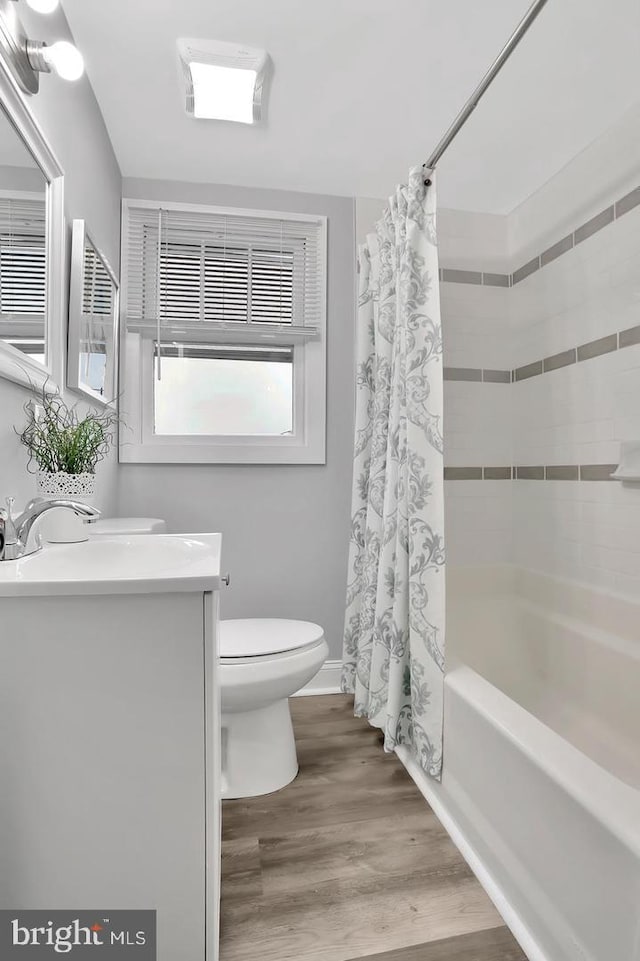 full bathroom featuring toilet, hardwood / wood-style floors, vanity, and shower / tub combo with curtain