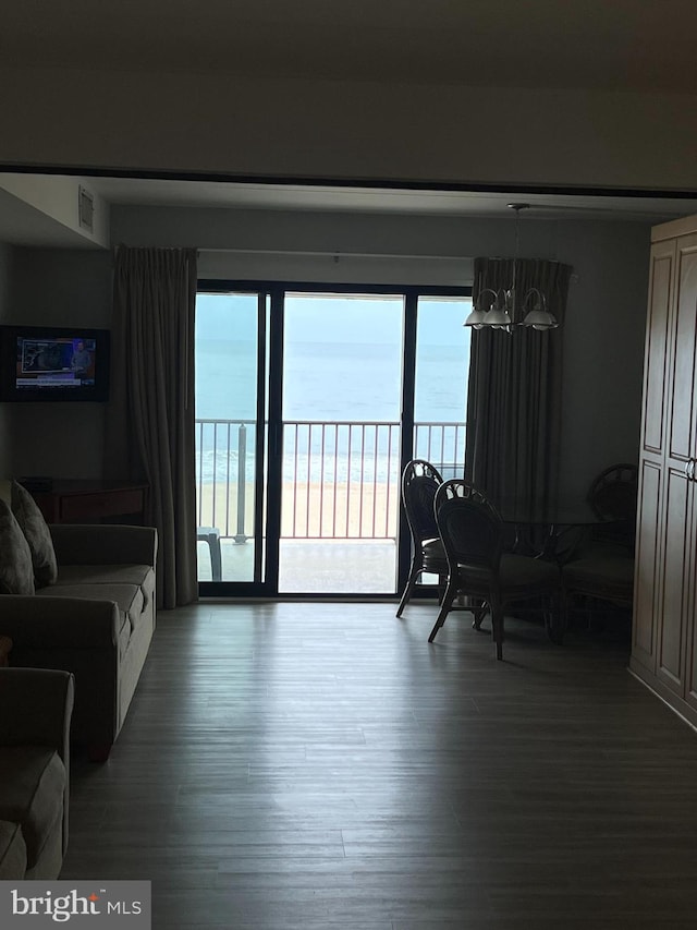 living room featuring a notable chandelier, dark hardwood / wood-style floors, and a water view