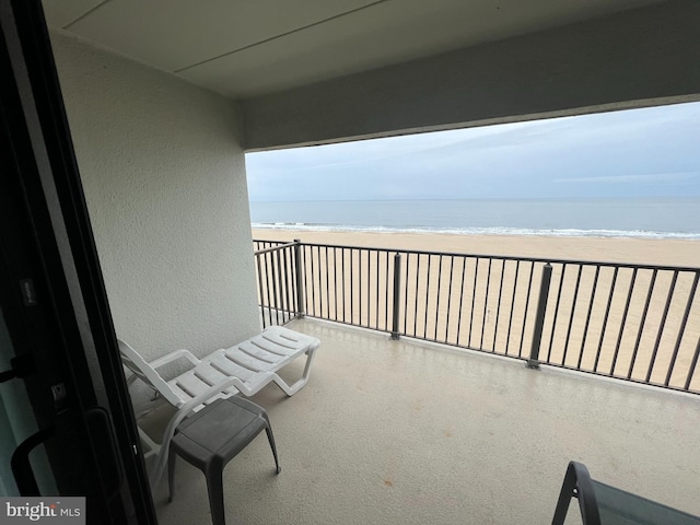 balcony featuring a beach view and a water view