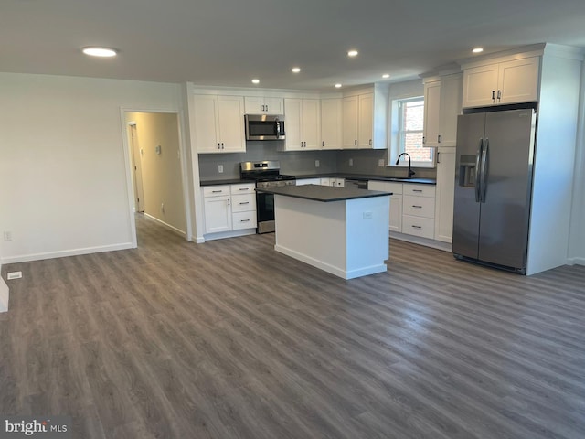 kitchen featuring appliances with stainless steel finishes, a center island, sink, dark hardwood / wood-style floors, and white cabinets