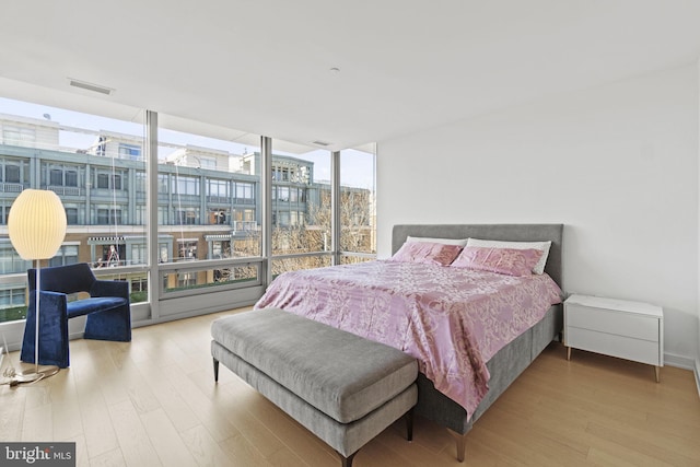 bedroom with expansive windows and wood-type flooring