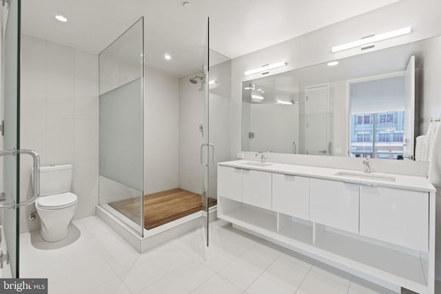 bathroom featuring toilet, vanity, a shower with door, and tile patterned flooring