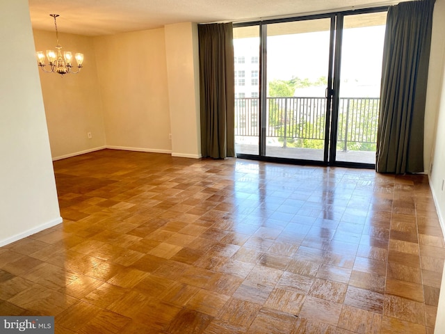 spare room with floor to ceiling windows and a chandelier