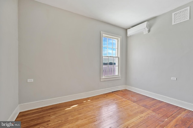 unfurnished room featuring hardwood / wood-style flooring and a wall unit AC