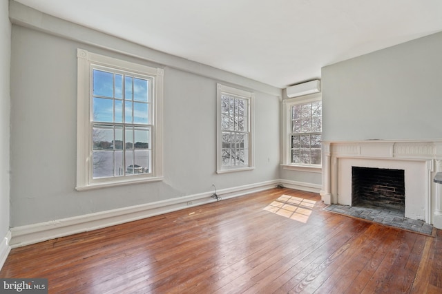 unfurnished living room featuring hardwood / wood-style floors and a wall unit AC