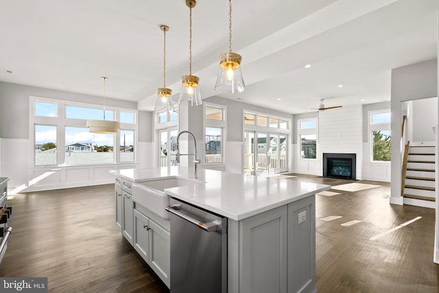 kitchen featuring dishwasher, decorative light fixtures, a center island with sink, and sink