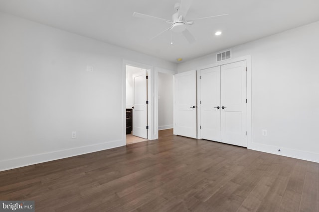 unfurnished bedroom with ceiling fan, ensuite bath, dark wood-type flooring, and a closet