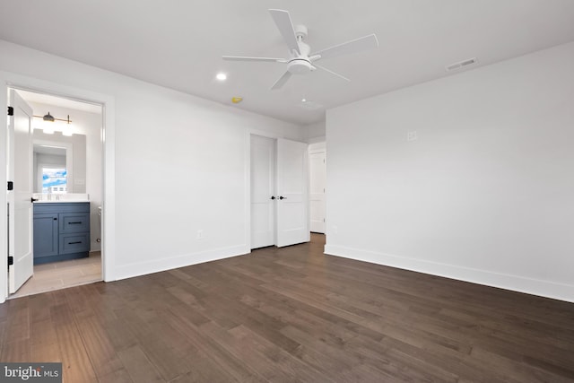 unfurnished bedroom with dark hardwood / wood-style flooring, ensuite bathroom, and ceiling fan