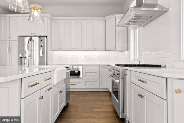 kitchen featuring wall chimney exhaust hood, dark wood-type flooring, hanging light fixtures, white cabinets, and high end range