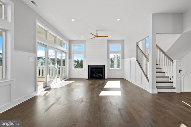 unfurnished living room with ceiling fan, a large fireplace, and dark hardwood / wood-style flooring