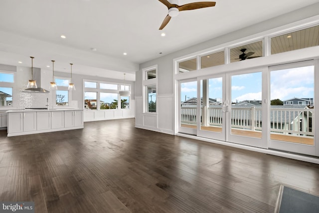 unfurnished living room featuring dark hardwood / wood-style flooring and ceiling fan