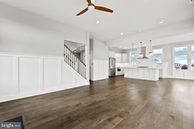 unfurnished living room featuring dark hardwood / wood-style floors, ceiling fan, and sink