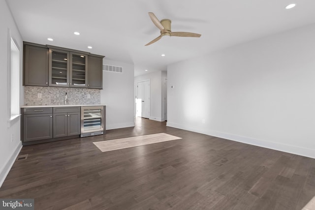 bar featuring dark hardwood / wood-style flooring, tasteful backsplash, beverage cooler, ceiling fan, and sink