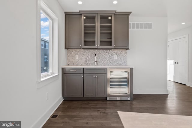 bar featuring decorative backsplash, sink, beverage cooler, and dark wood-type flooring