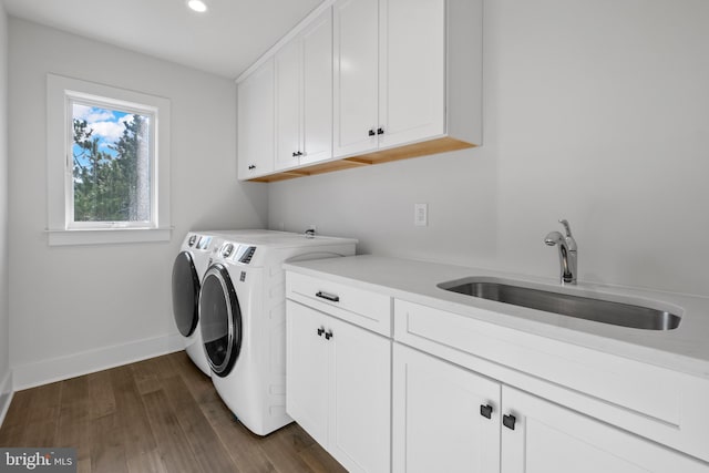 clothes washing area with cabinets, dark hardwood / wood-style flooring, washer and dryer, and sink