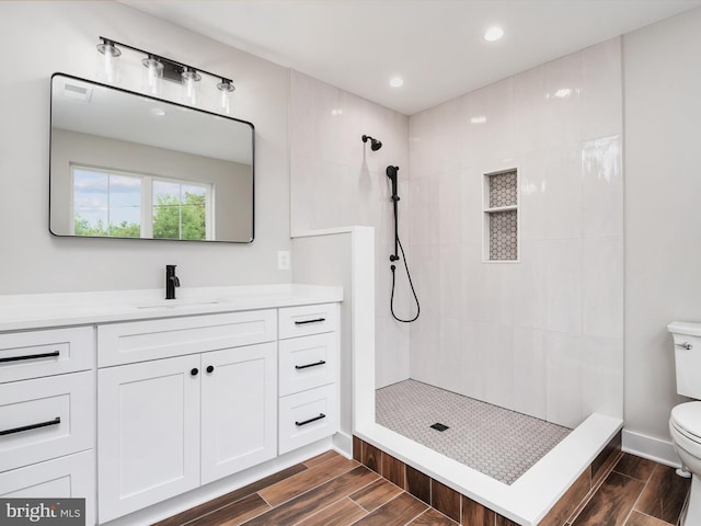 bathroom with a tile shower, vanity, and toilet