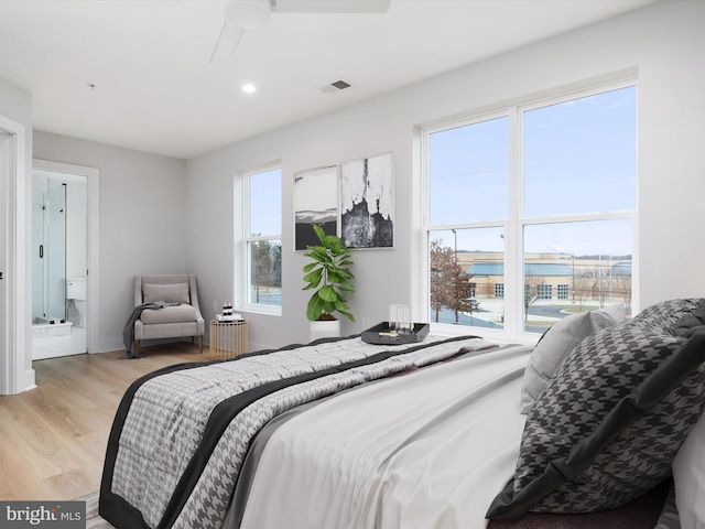 bedroom with multiple windows, light hardwood / wood-style floors, ceiling fan, and ensuite bathroom