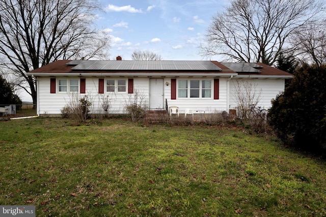 single story home featuring solar panels and a front lawn