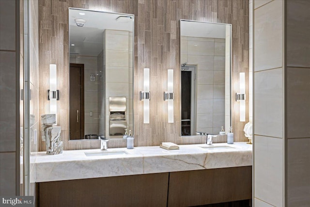 bathroom featuring double vanity and tile walls