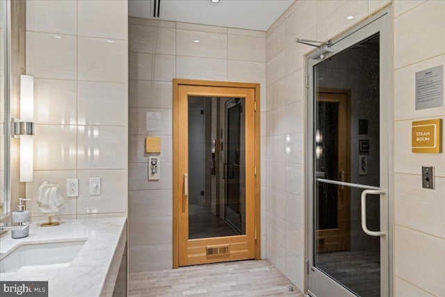 bathroom with tile walls, sink, and hardwood / wood-style flooring