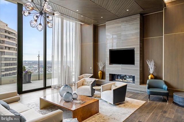 living room with an inviting chandelier, a wall of windows, hardwood / wood-style floors, and a large fireplace