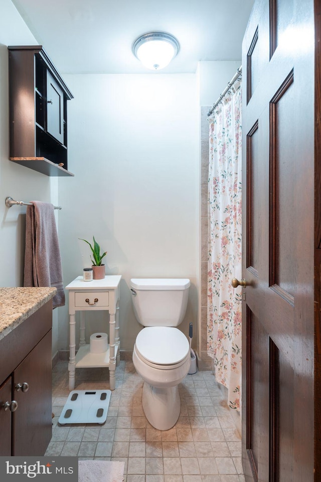 bathroom featuring tile flooring, toilet, and vanity