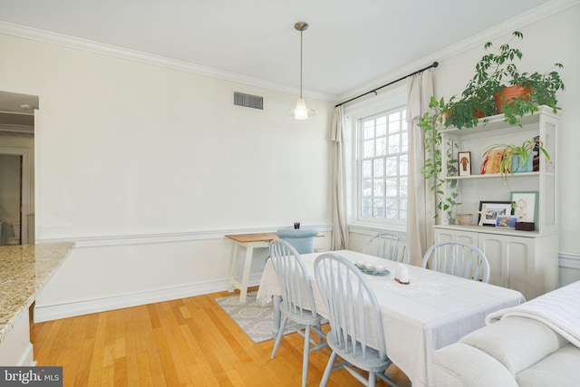 dining space featuring crown molding and light hardwood / wood-style floors