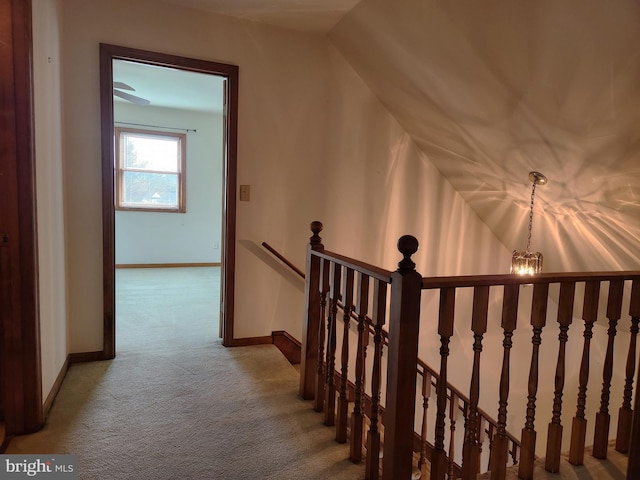 hall featuring carpet flooring, lofted ceiling, and an inviting chandelier