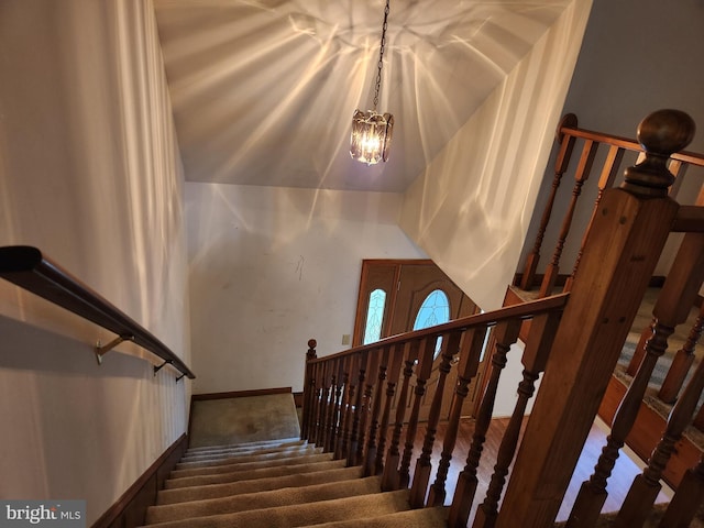 stairway with carpet floors and an inviting chandelier