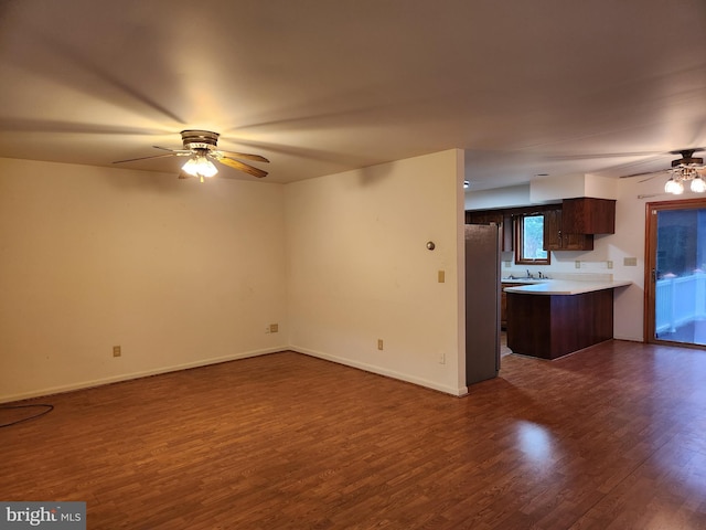 unfurnished living room featuring dark hardwood / wood-style floors, ceiling fan, and sink