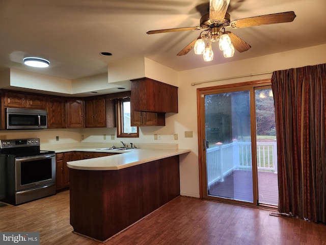 kitchen featuring kitchen peninsula, a wealth of natural light, stainless steel appliances, sink, and wood-type flooring