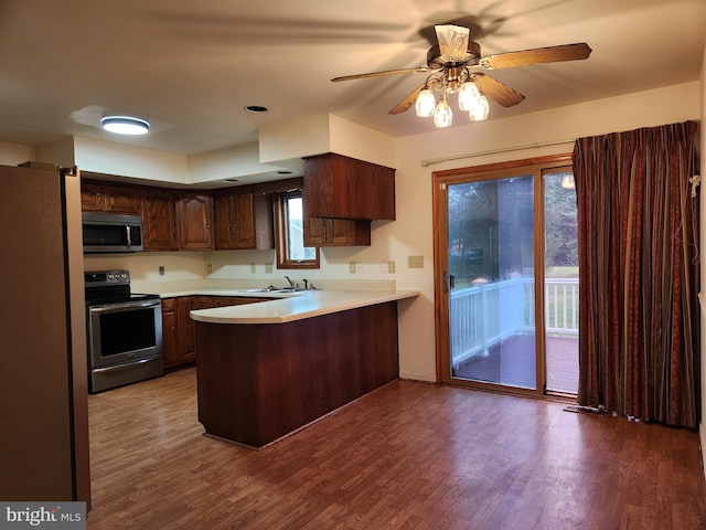 kitchen featuring sink, ceiling fan, appliances with stainless steel finishes, dark hardwood / wood-style flooring, and kitchen peninsula